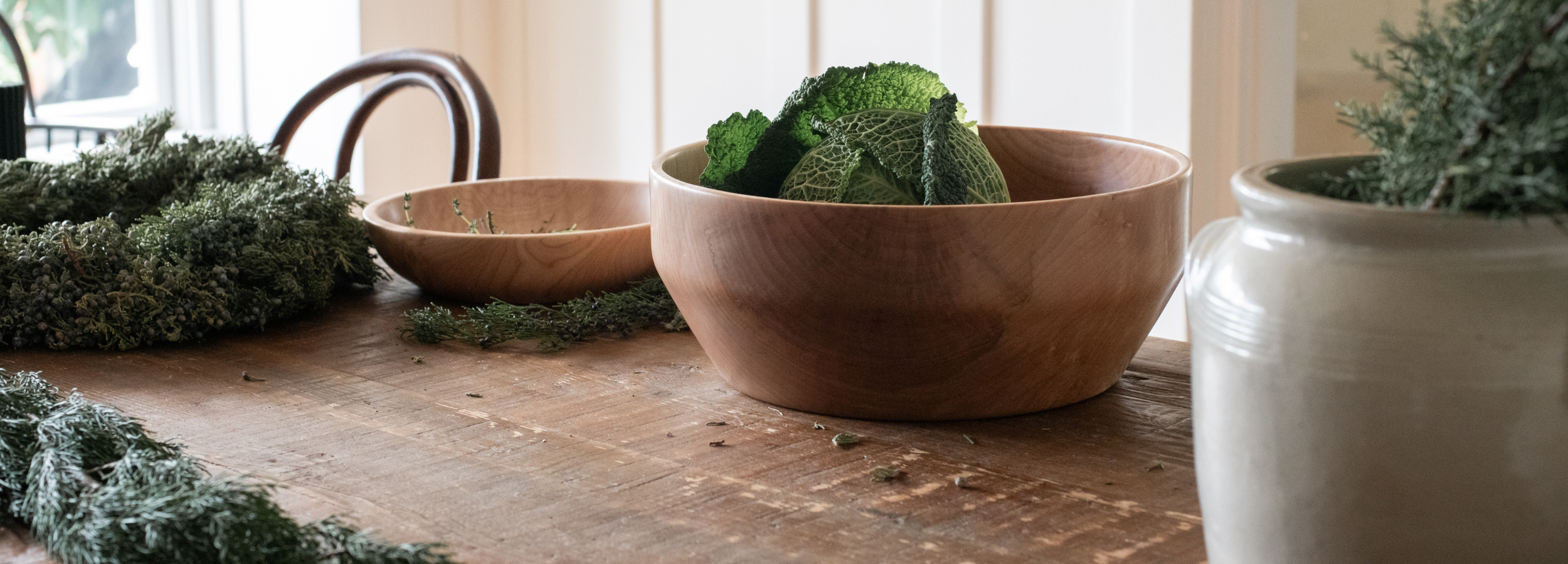 wooden bowls and greens on a harvest table