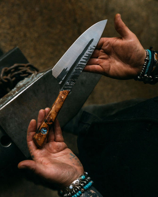 Ryan Fogarty holding a large knife with a wooden handle against a dark background