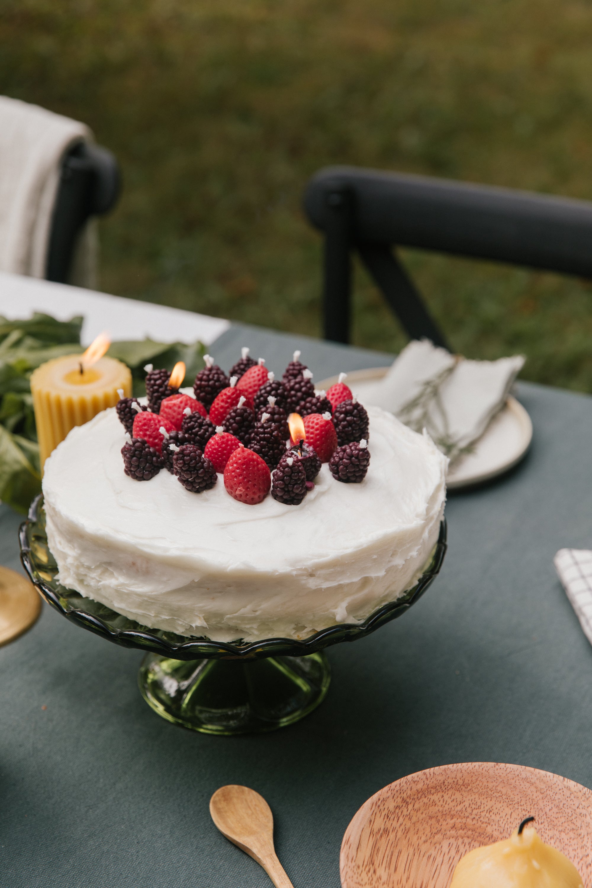 Decorative cake with berries candles on a table outdoors