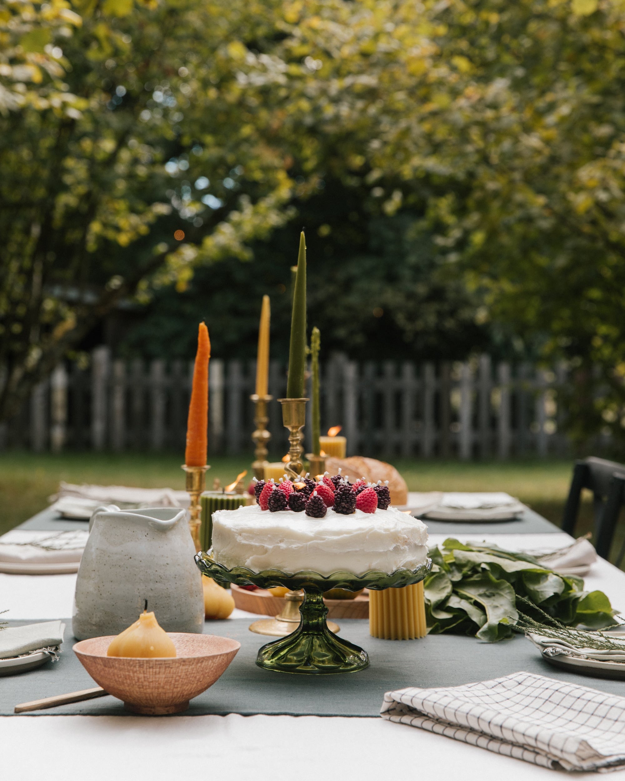 Decorative table setting with a cake and candles outdoors
