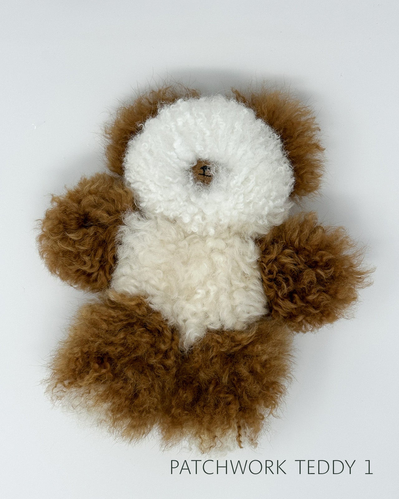 Patchwork teddy bear made of brown and white hair on a white background