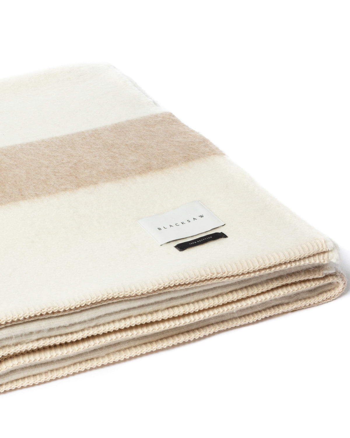 A folded cream and beige striped wool blanket with a small white brand label, shown on a clean white background.
