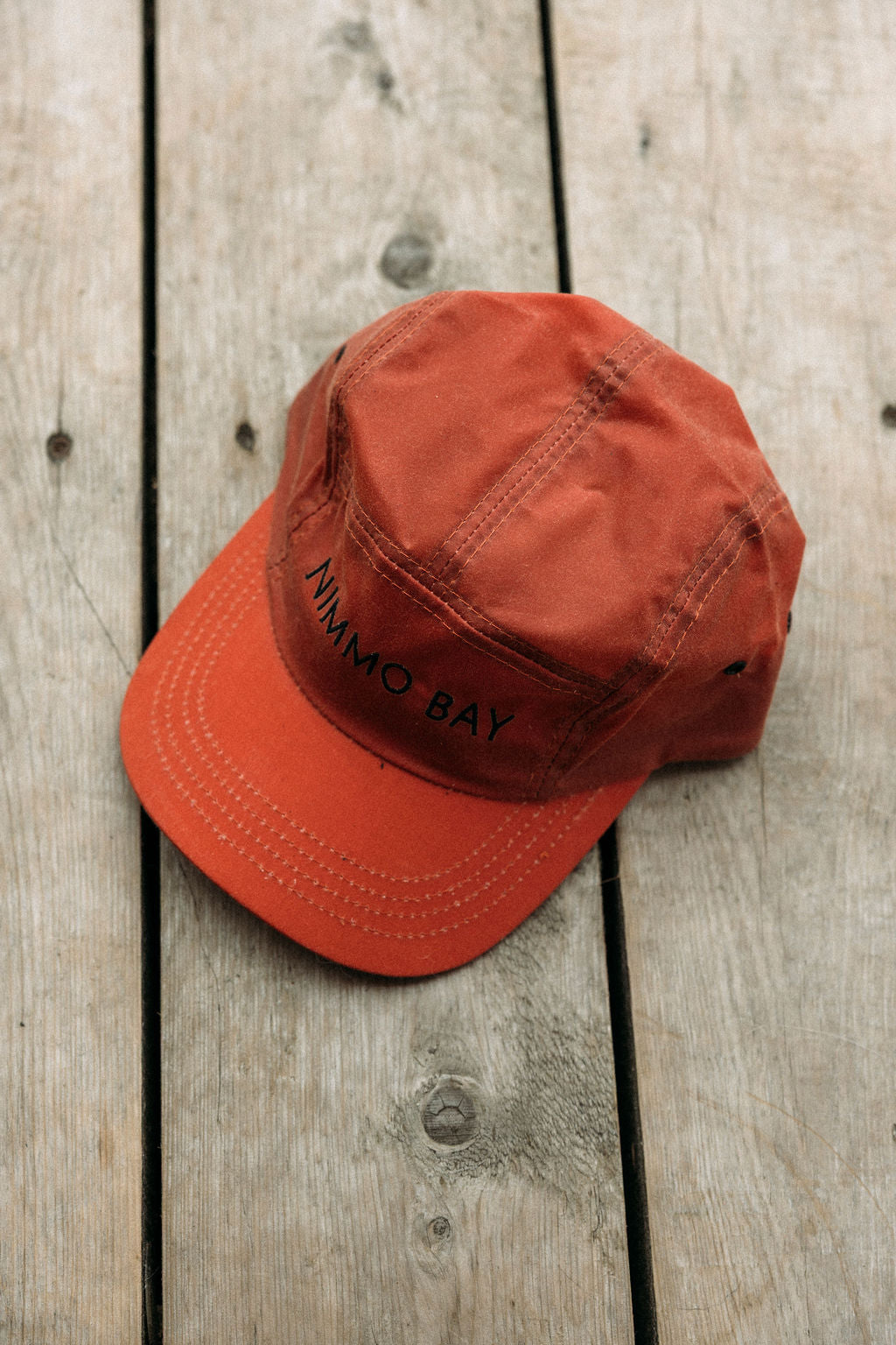 Red anian tin cap with 'Nimmo Bay' text on a wooden surface