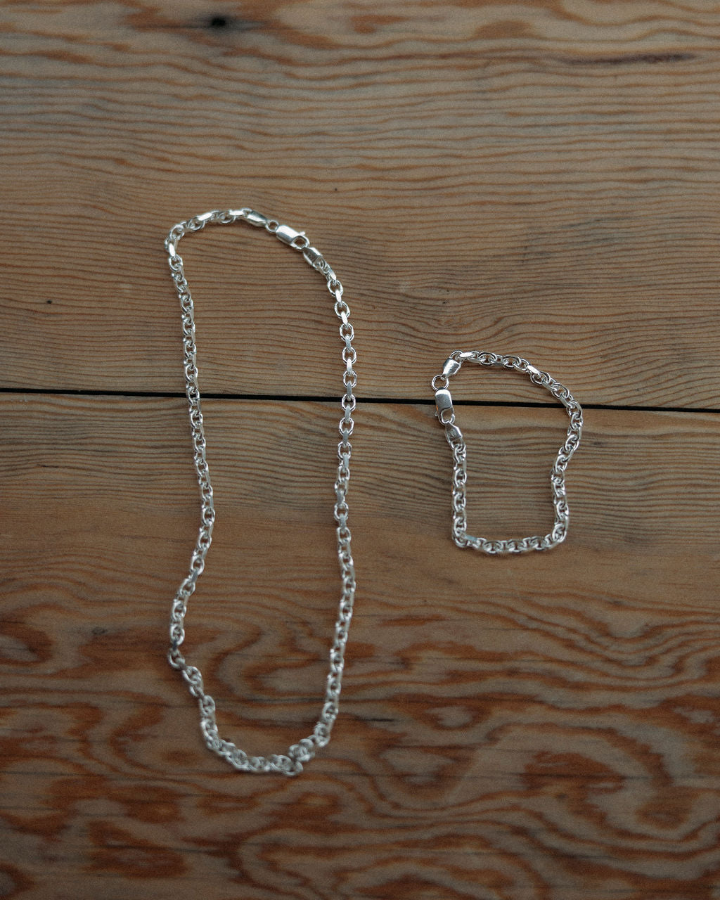 Sow Song Sterling Silver chain link necklace and bracelet on a wooden surface