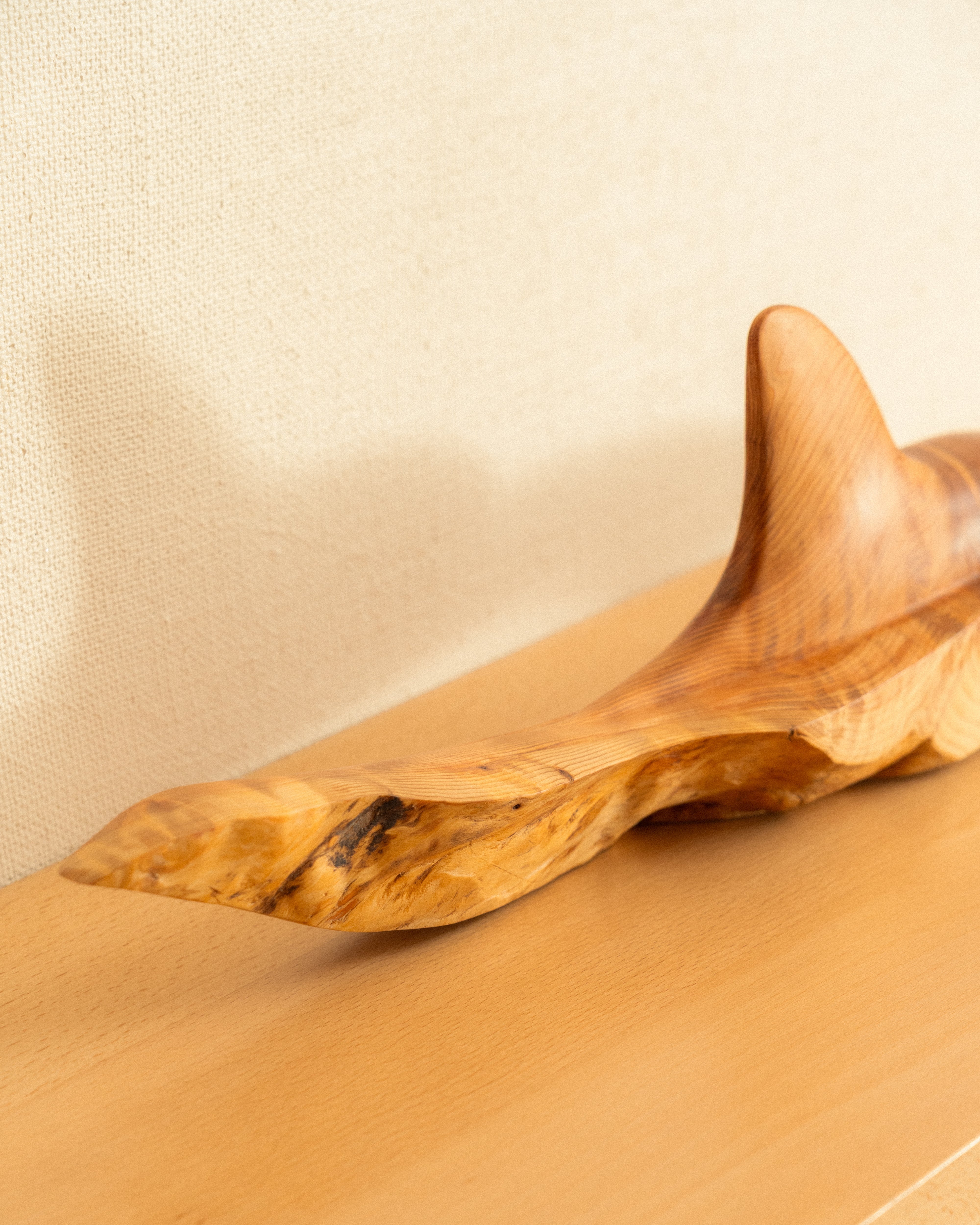 Wooden orca carving on a beige surface with a neutral background