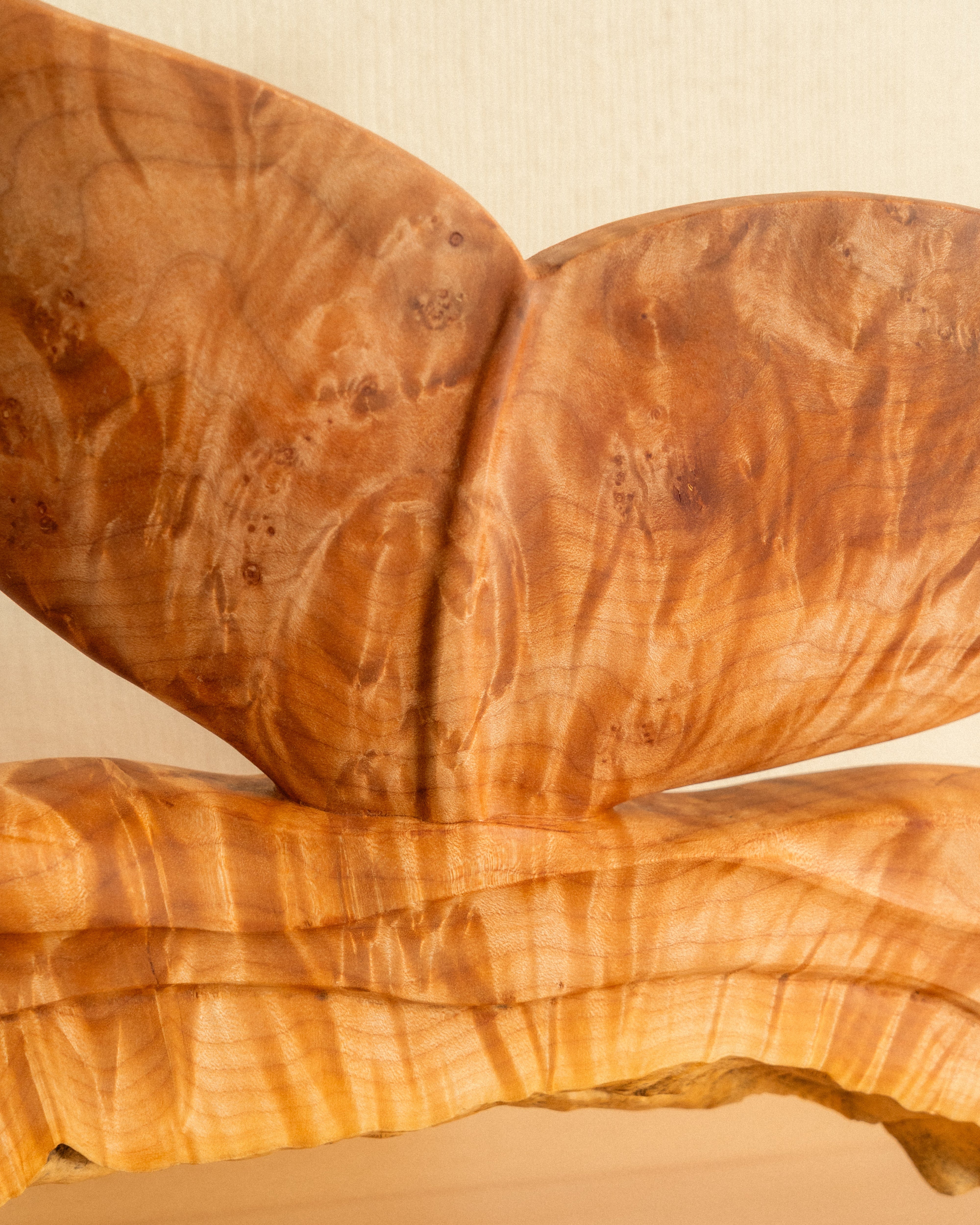 Wooden sculpture of a whale tale on a wooden shelf with a plain background
