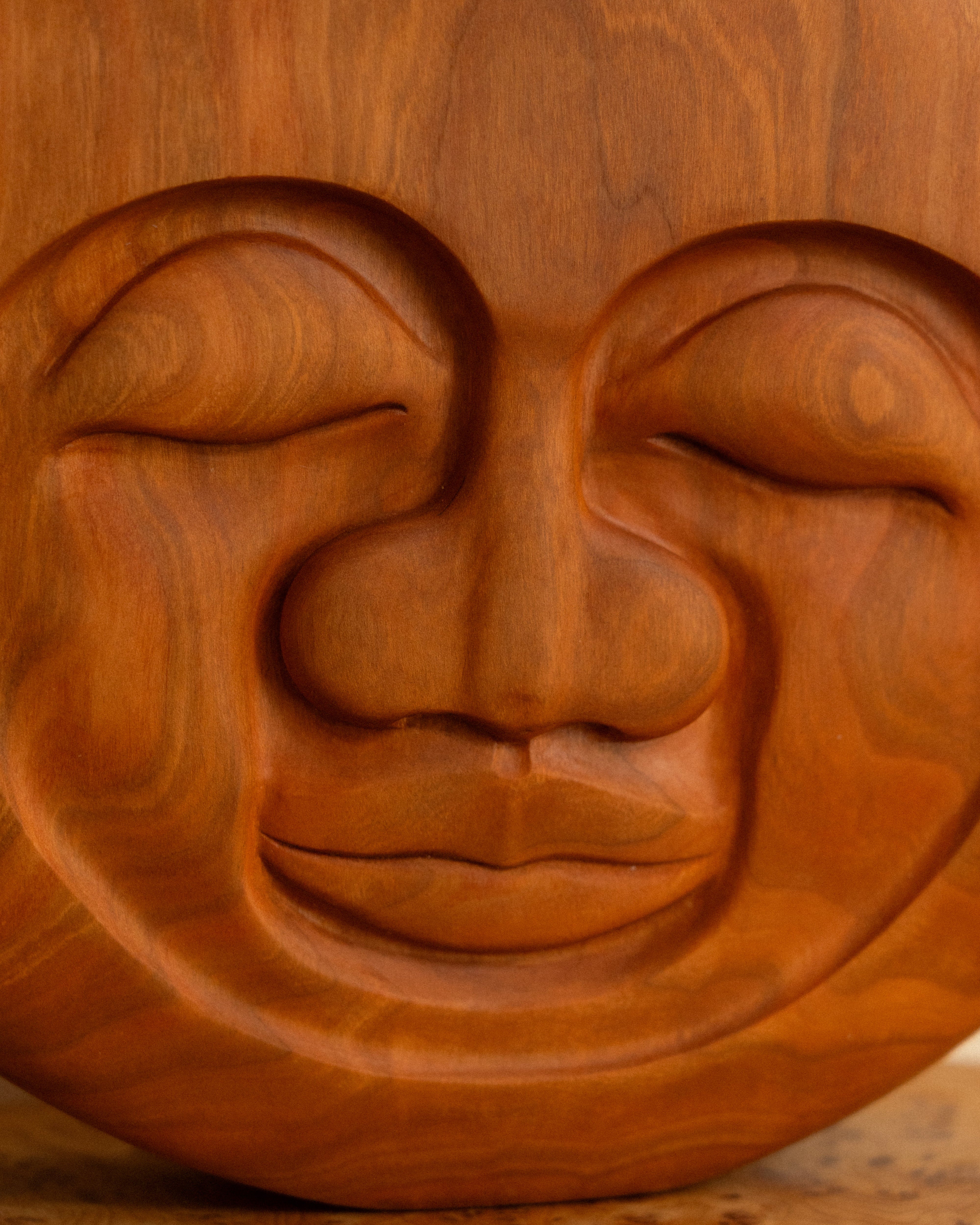 Wooden face sculpture with closed eyes on a wooden surface