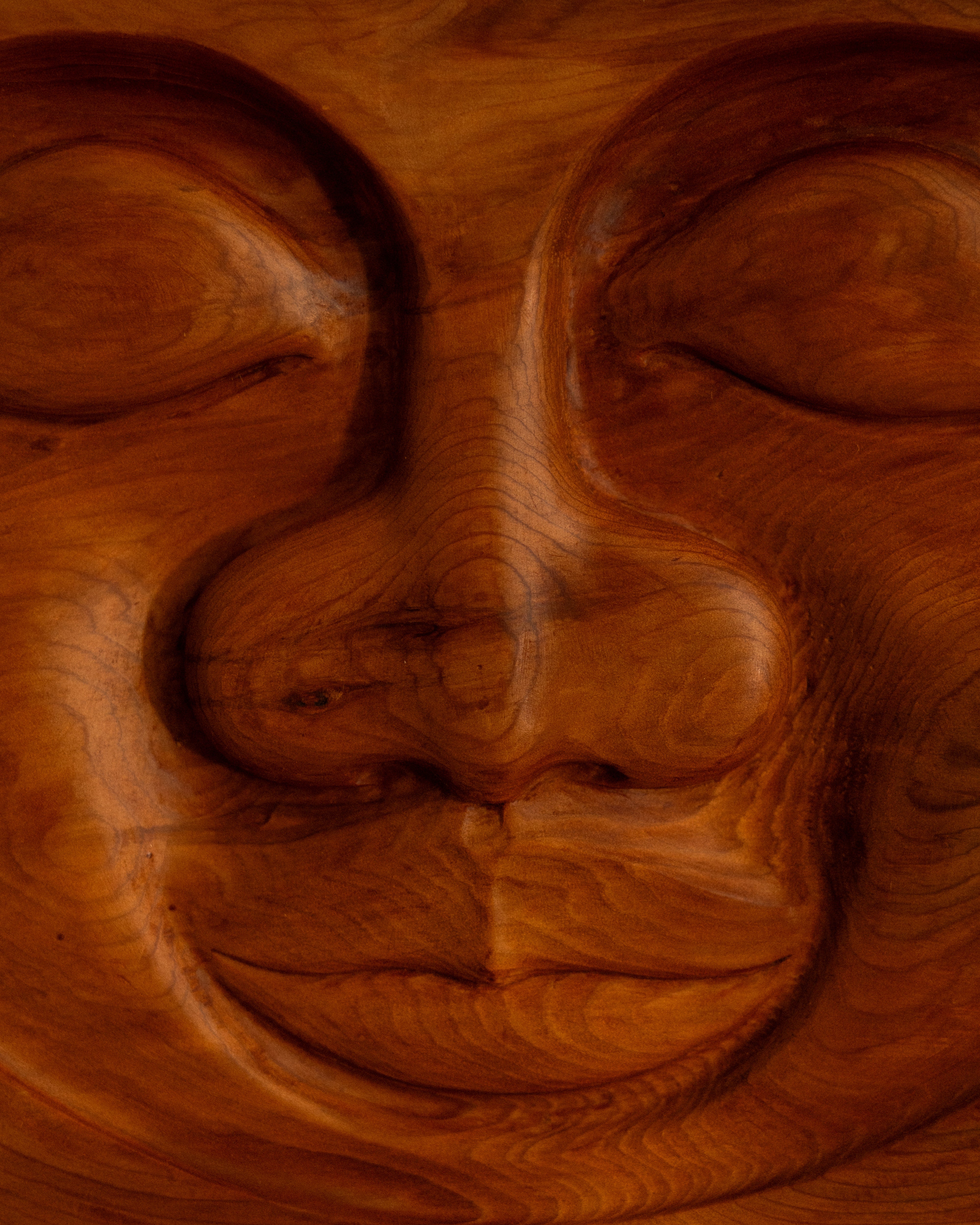 Wooden carving of a face with closed eyes. Serenity Sun carving by Bjorn Banke.