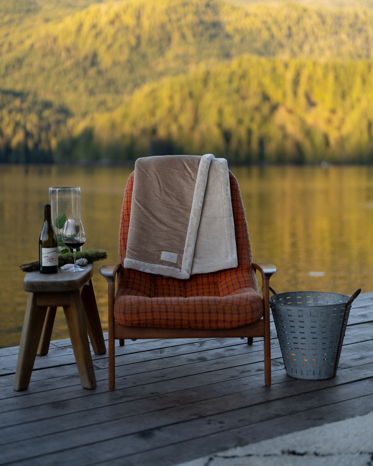 a nimmo bay boat blanket draped over an orange chair with trees in the background