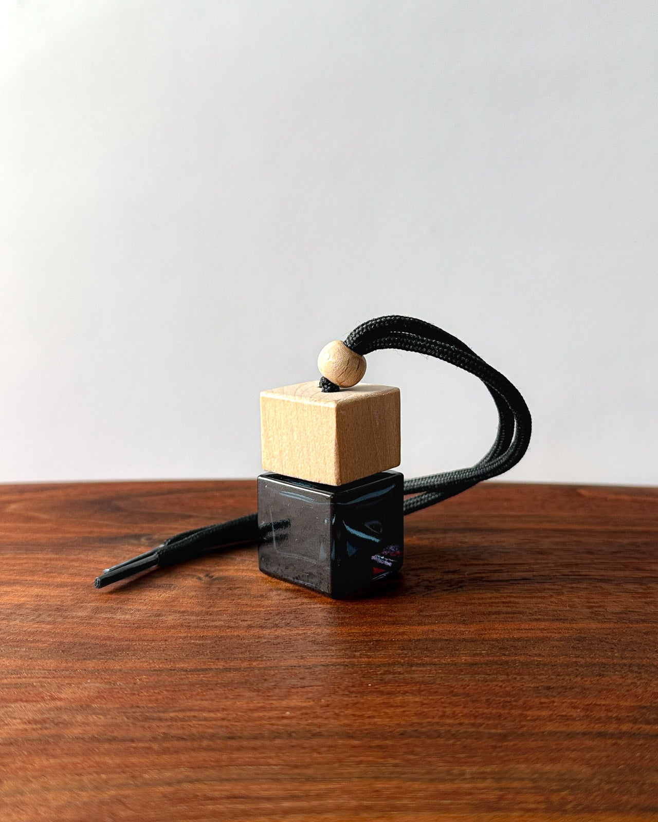 Oil diffuser with a wooden pendant and black cord on a wooden surface
