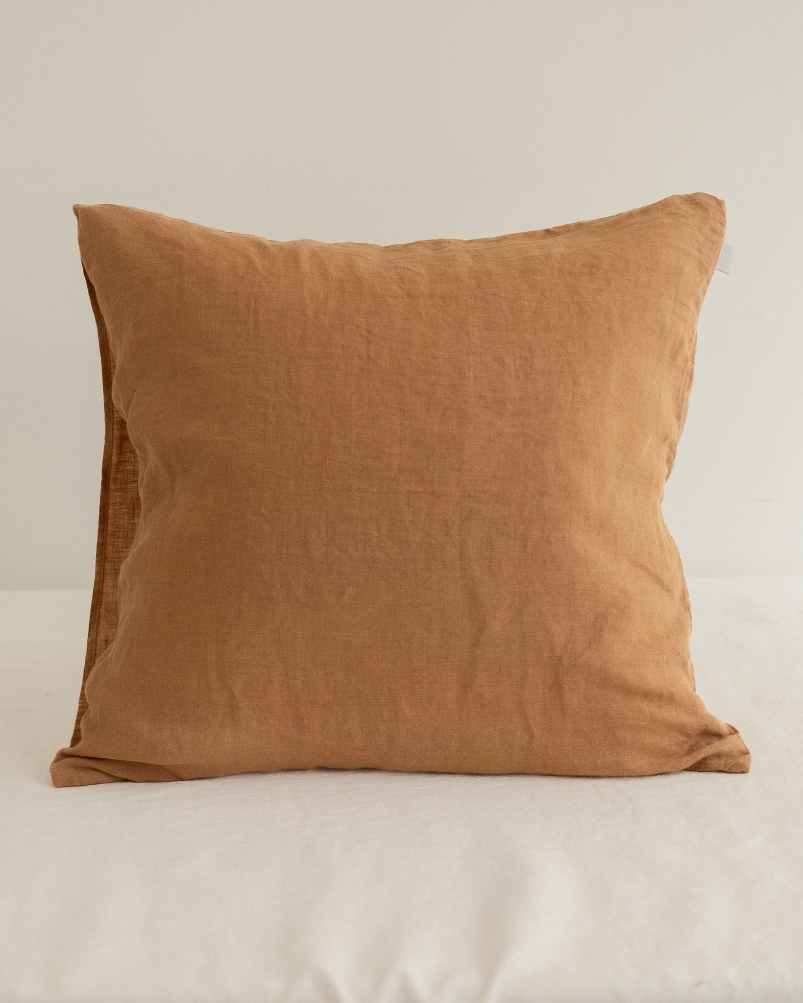 Brown pillow on a white surface with a neutral background