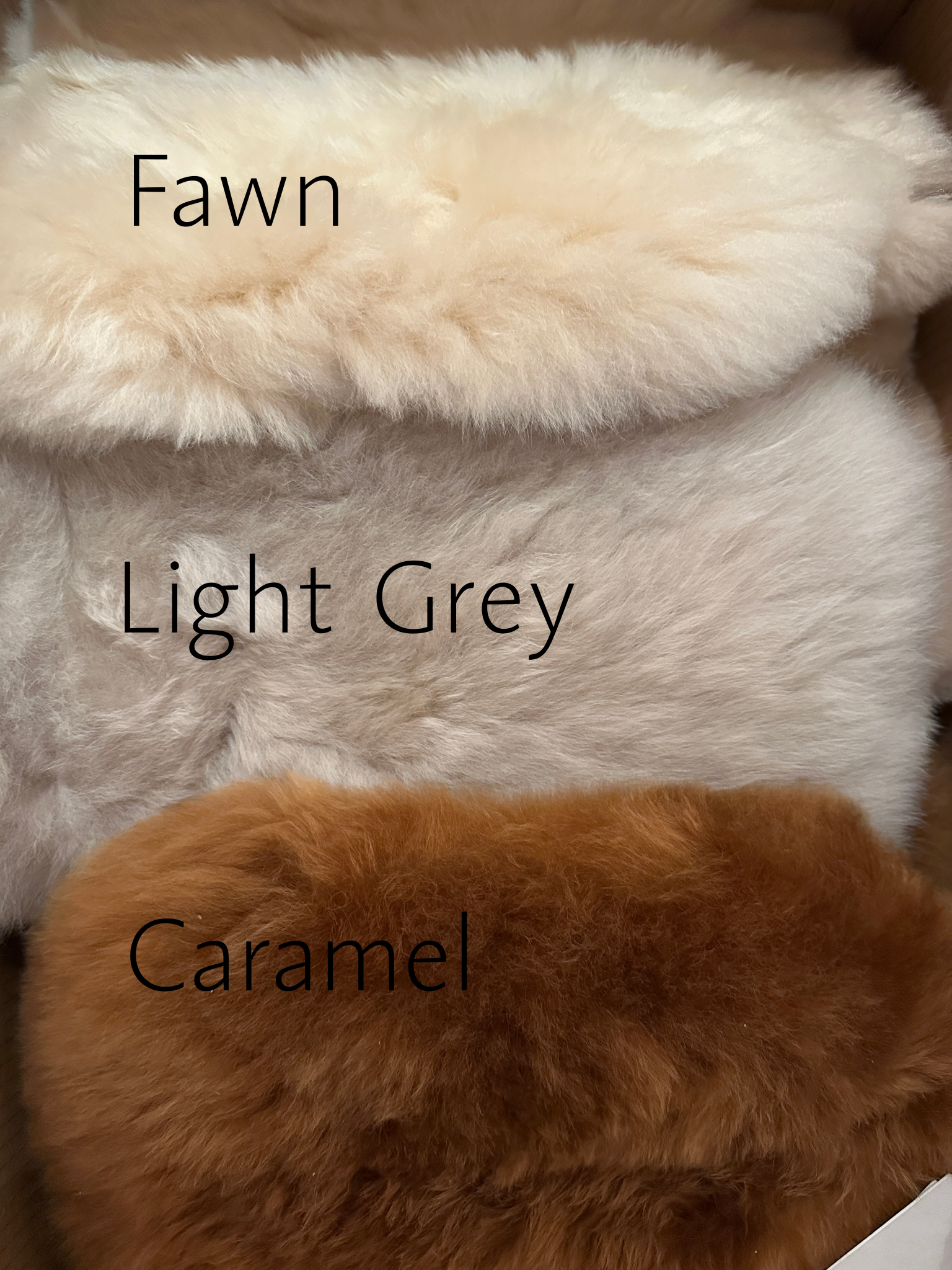 Close-up of Hot Water Bottle fur samples labeled 'Fawn', 'Light Grey', and 'Caramel' on a textured background.