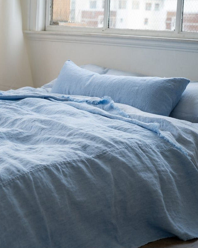 Blue bedding set on a bed with a window in the background
