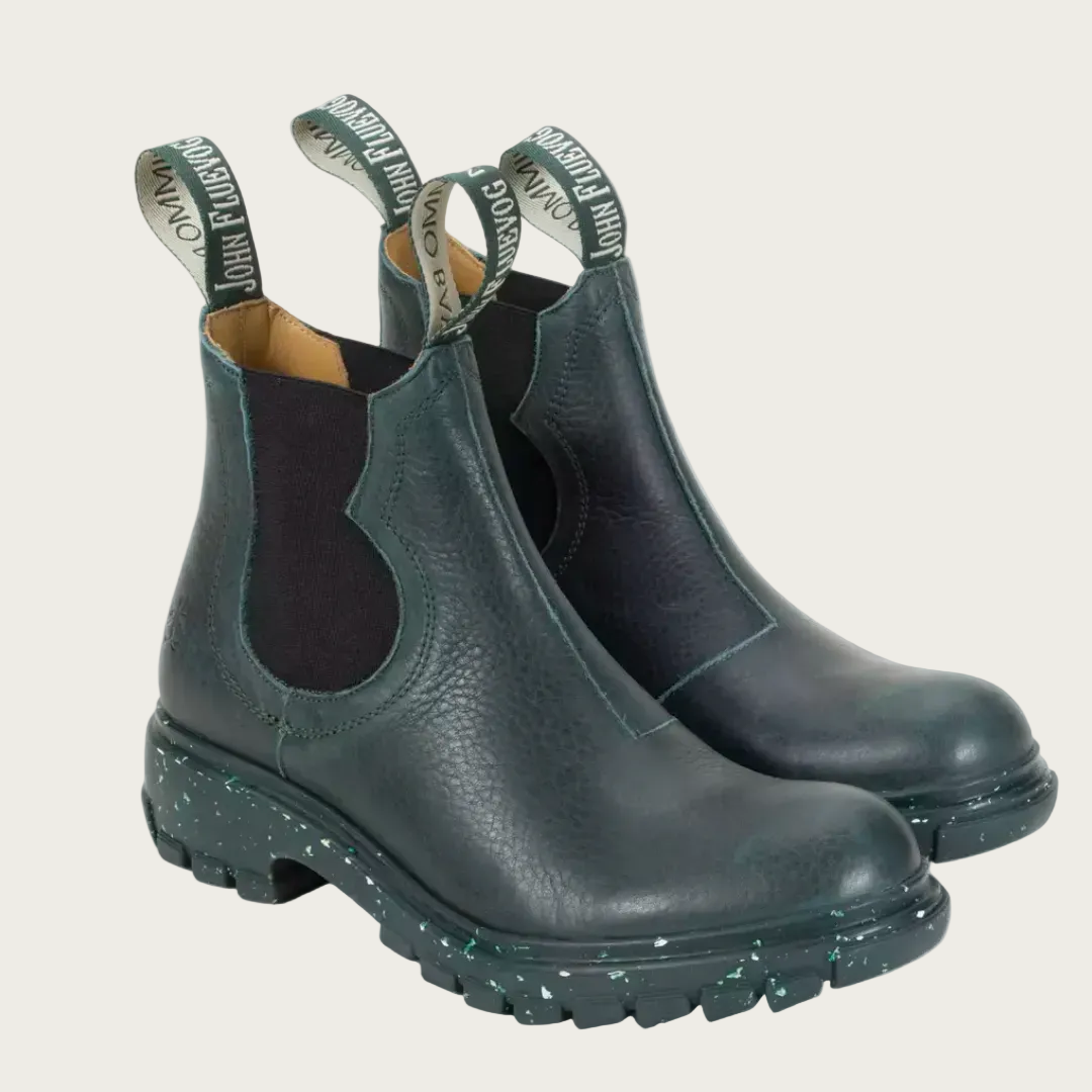A pair of dark green Fluevog Official Jeudi Chelsea Boots with visible soft leather texture and unique patterned bootlace eyelets.