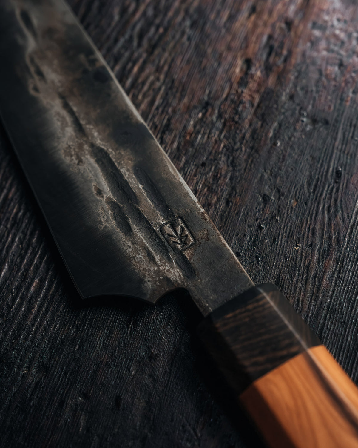 A close up of a leechtown blacksmith forged steel knife on a black wooden background