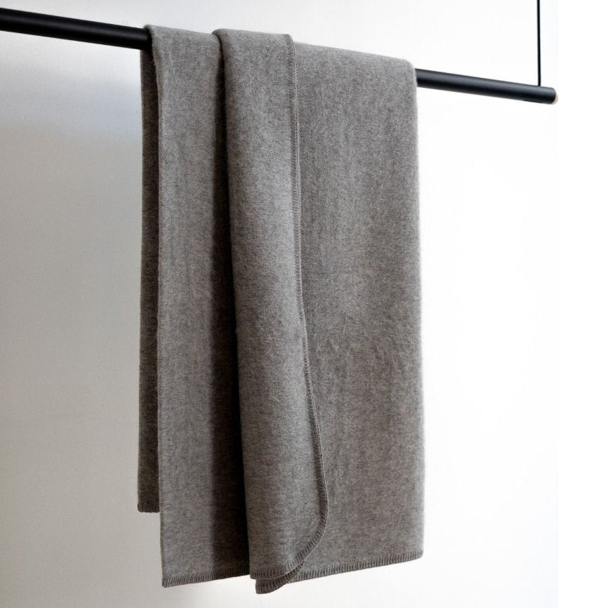 Gray towel draped over a black towel rack on a white background