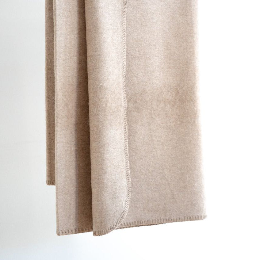 Beige blanket draped over a white surface