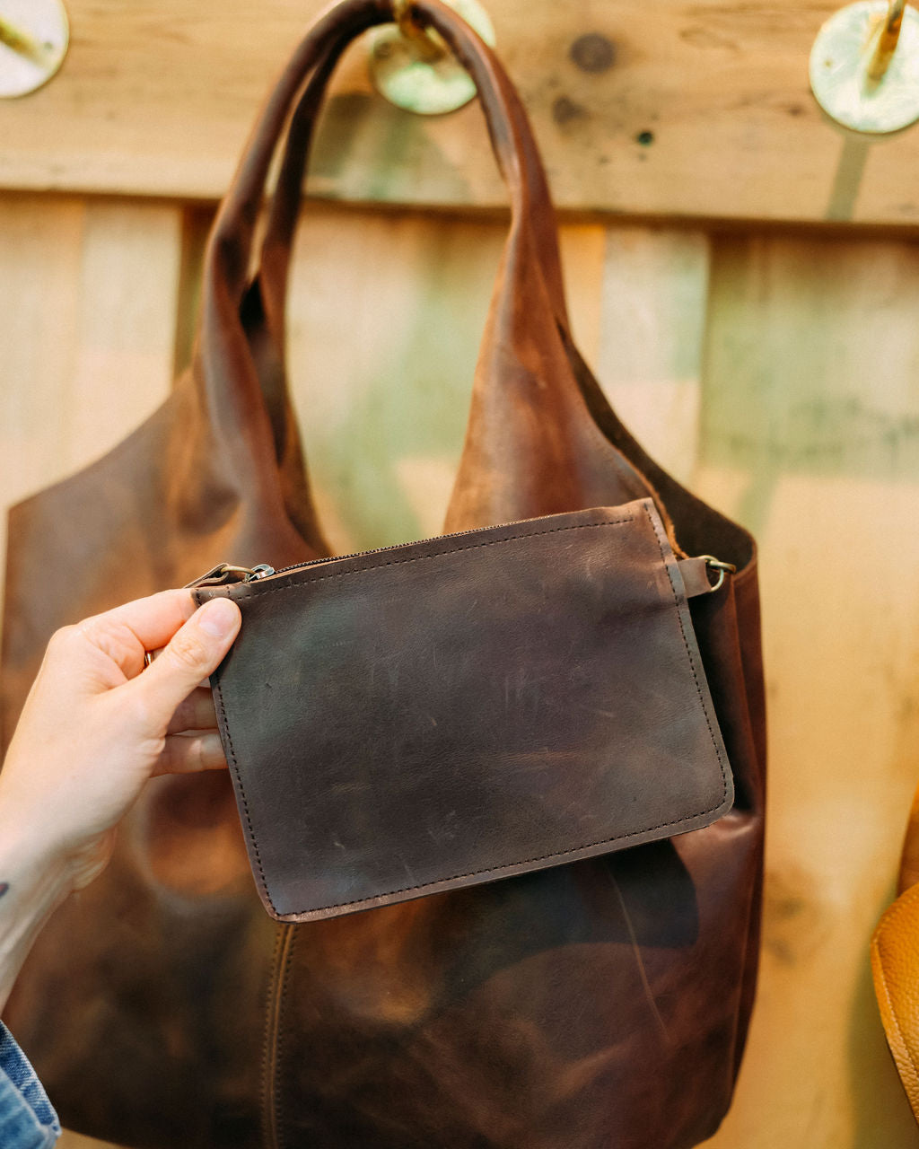 Brown leather bag held by a hand with a blurred background