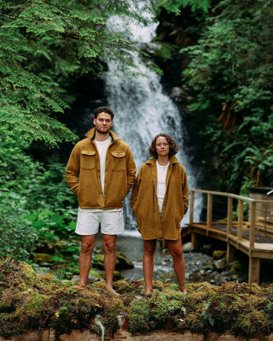 Two people standing in front of a waterfall in a forest