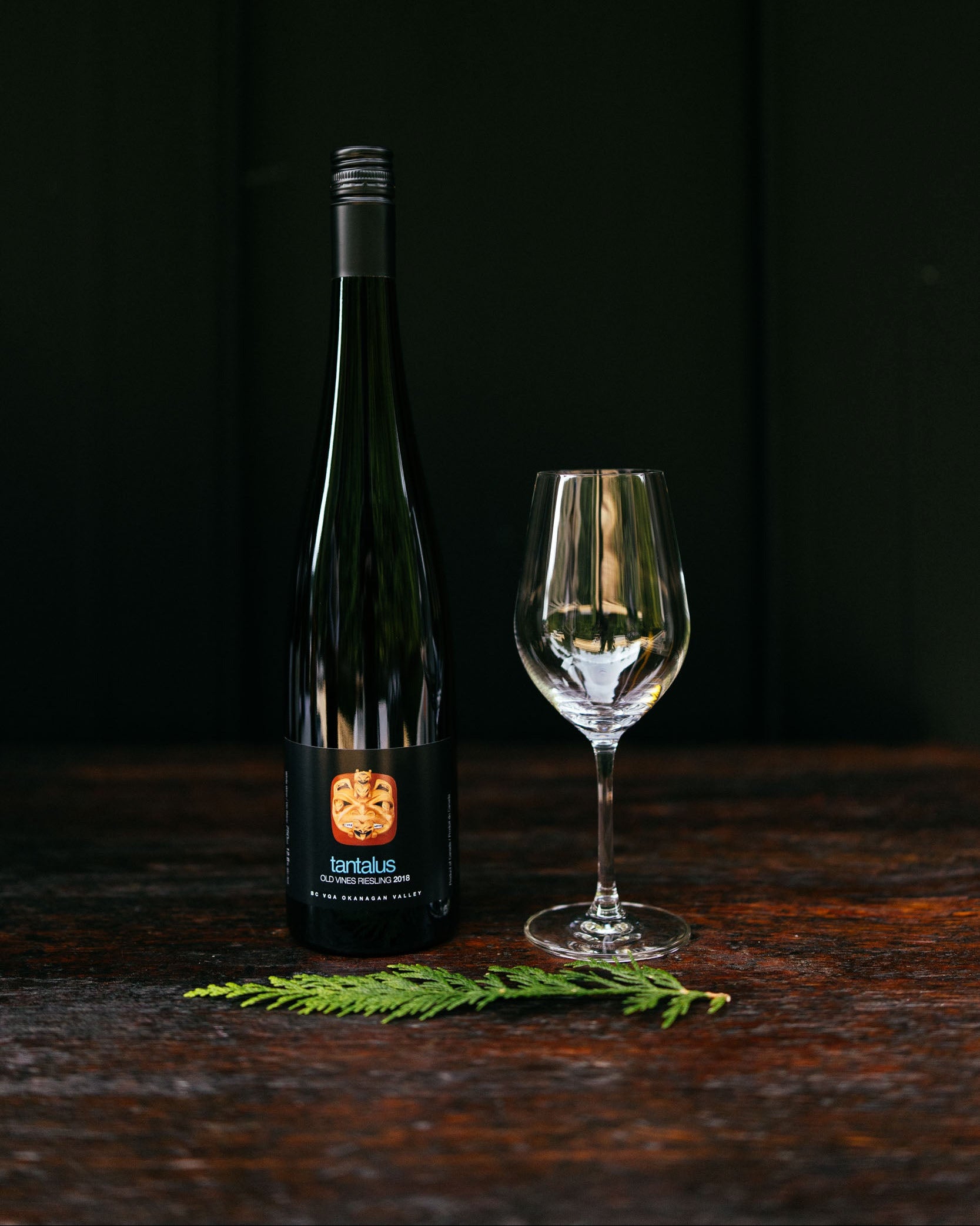 Wine bottle and glass on a dark wooden surface with a black background