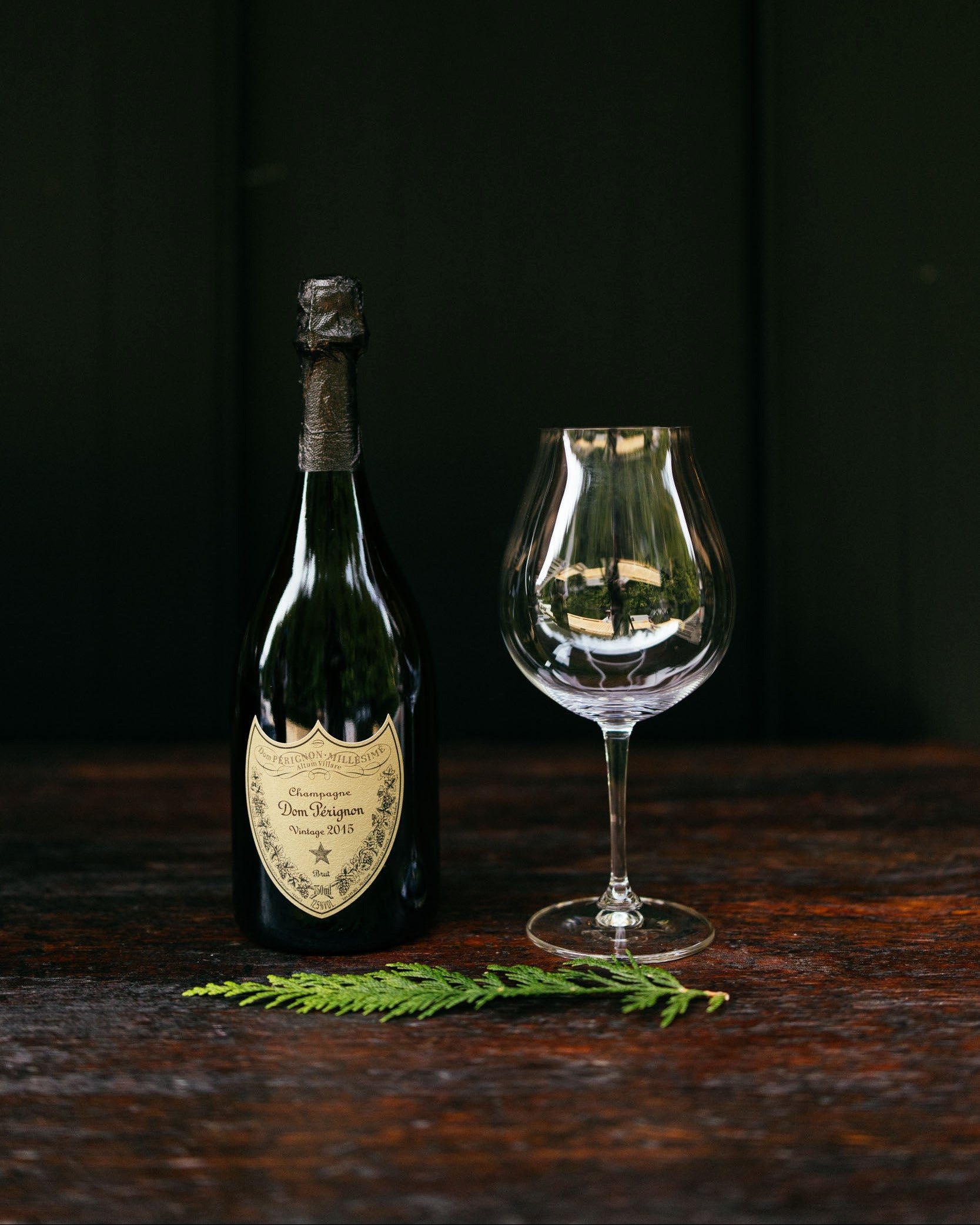 Wine bottle with cork and a glass on a dark wooden surface