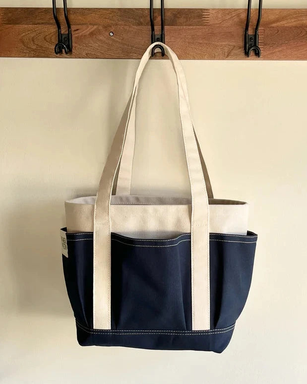Navy Rather green amiga petite tote bag hanging on a wooden rack with hooks.