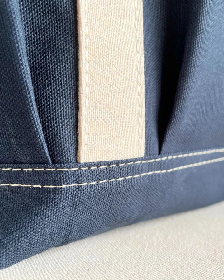 Close-up of blue fabric with white stitching on a beige background