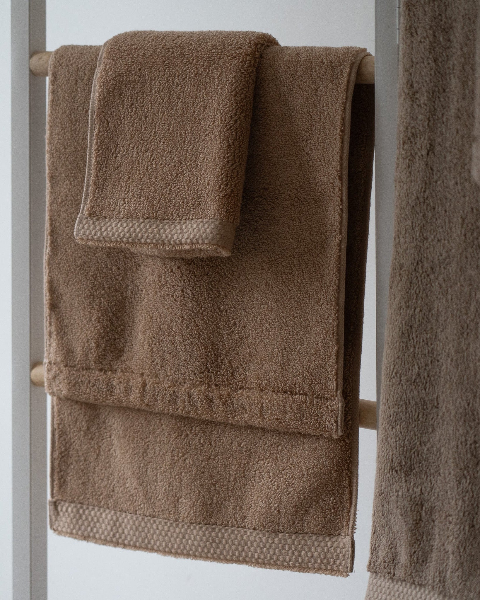 Brown towels hanging on a towel rack against a white background
