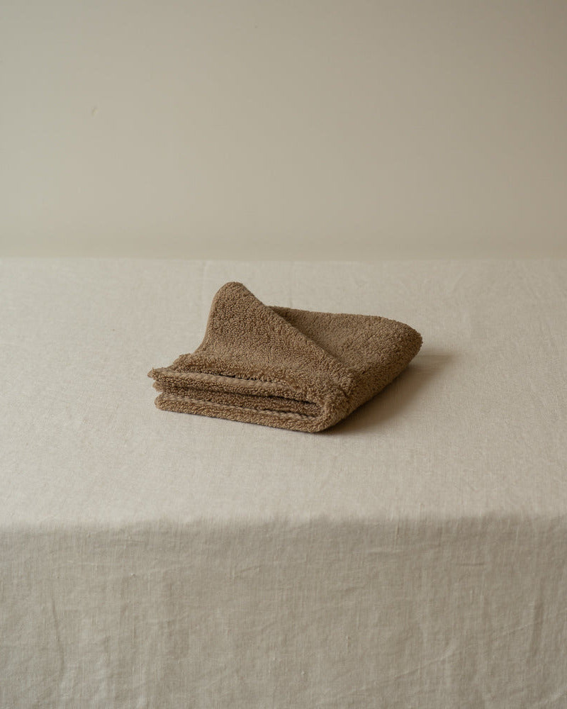 Folded beige towel on a textured surface with a neutral background