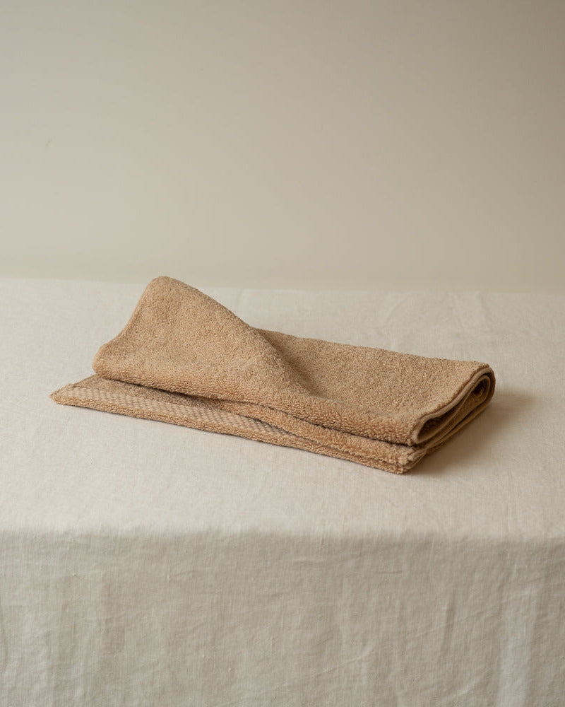 Folded beige towel on a textured white surface