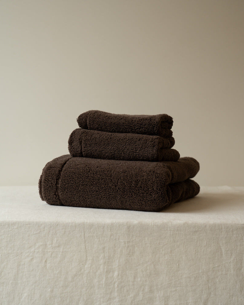 Stack of brown towels on a beige surface with a neutral background