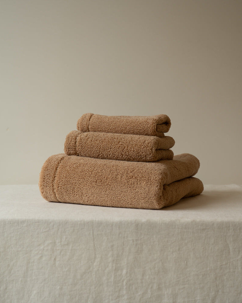 Stack of brown towels on a textured surface with a neutral background