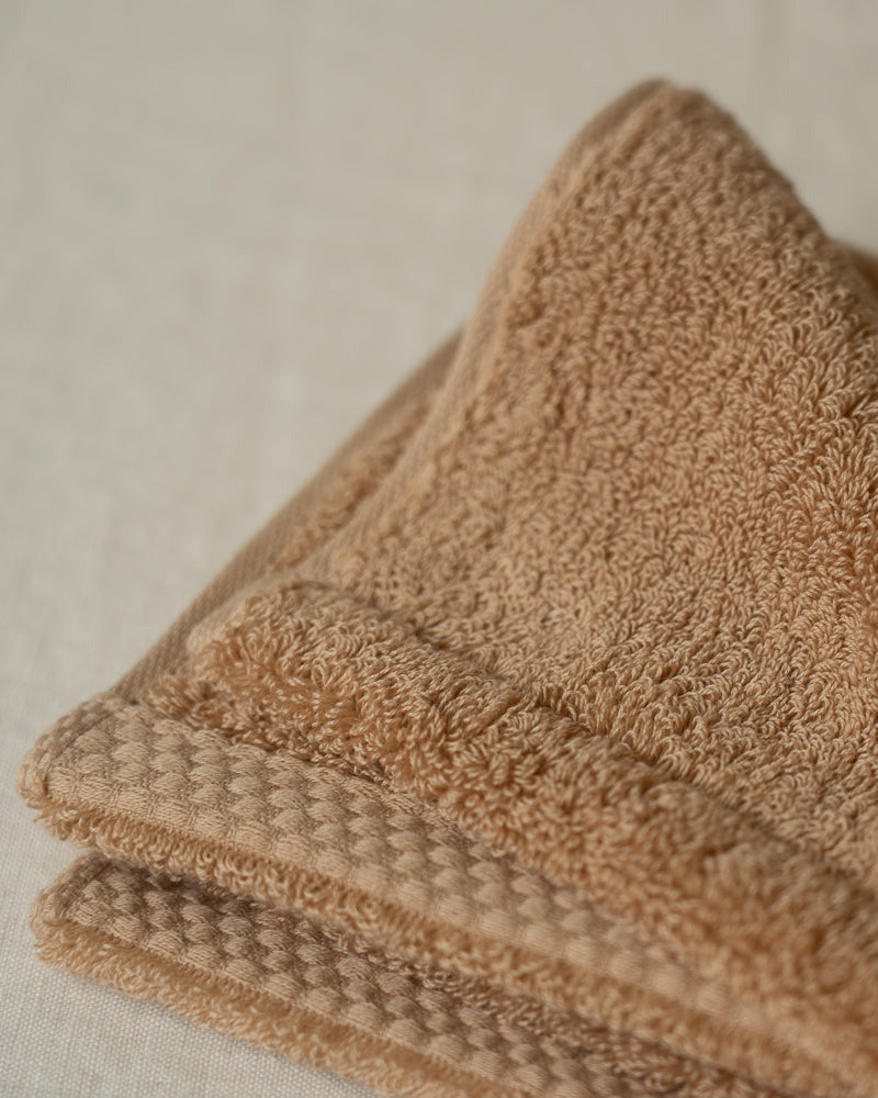 Folded brown towel on a neutral background