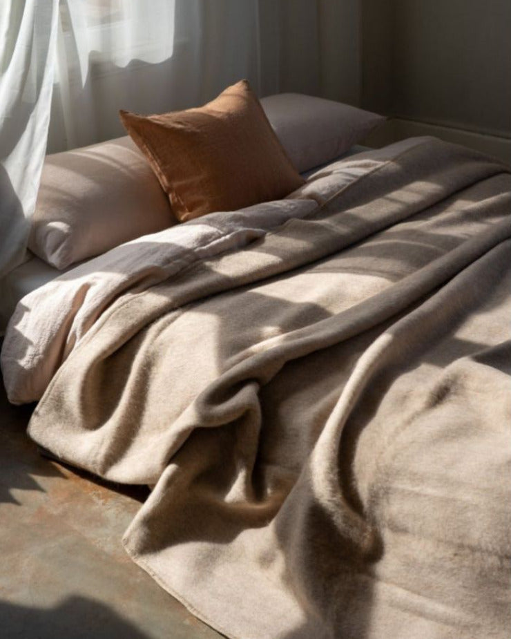 Cozy bed with beige blanket and pillow in a softly lit room