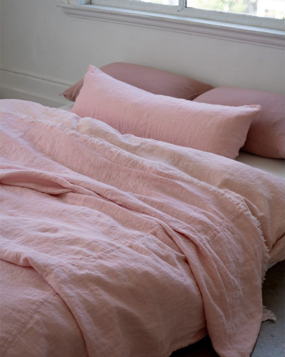 Pink bedding set on a bed with a window in the background