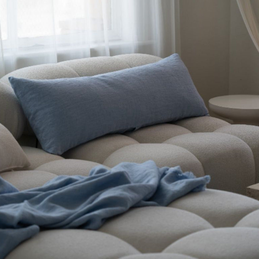 Beige sofa with a blue pillow and blanket in a living room setting