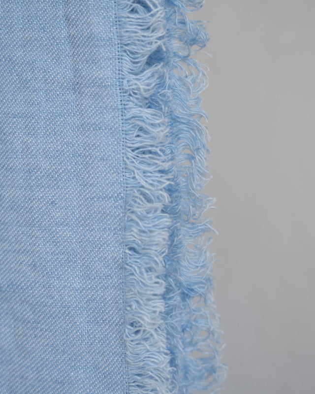 Light blue fabric with frayed edge on a gray background