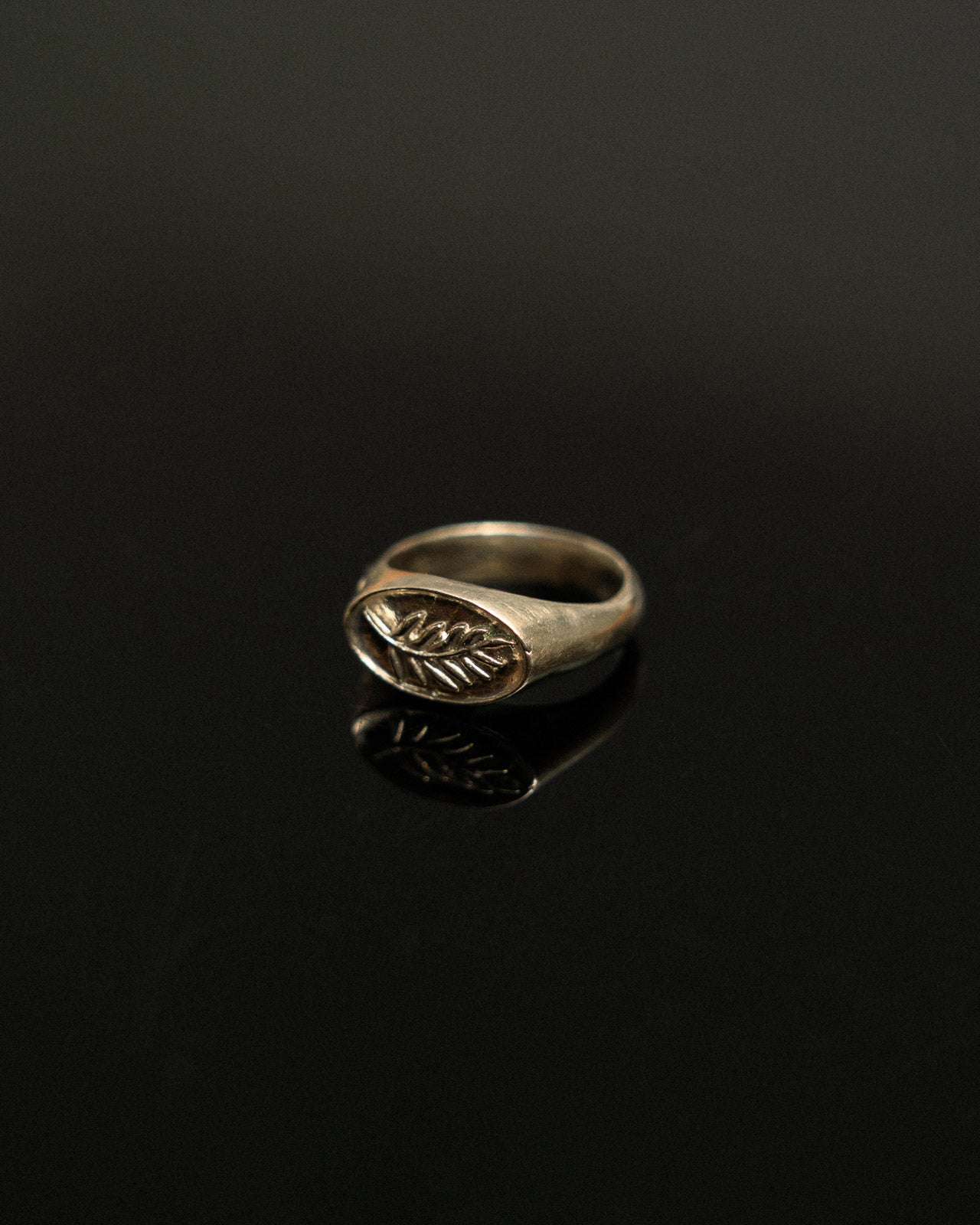 Silver ring with leaf design on a black background