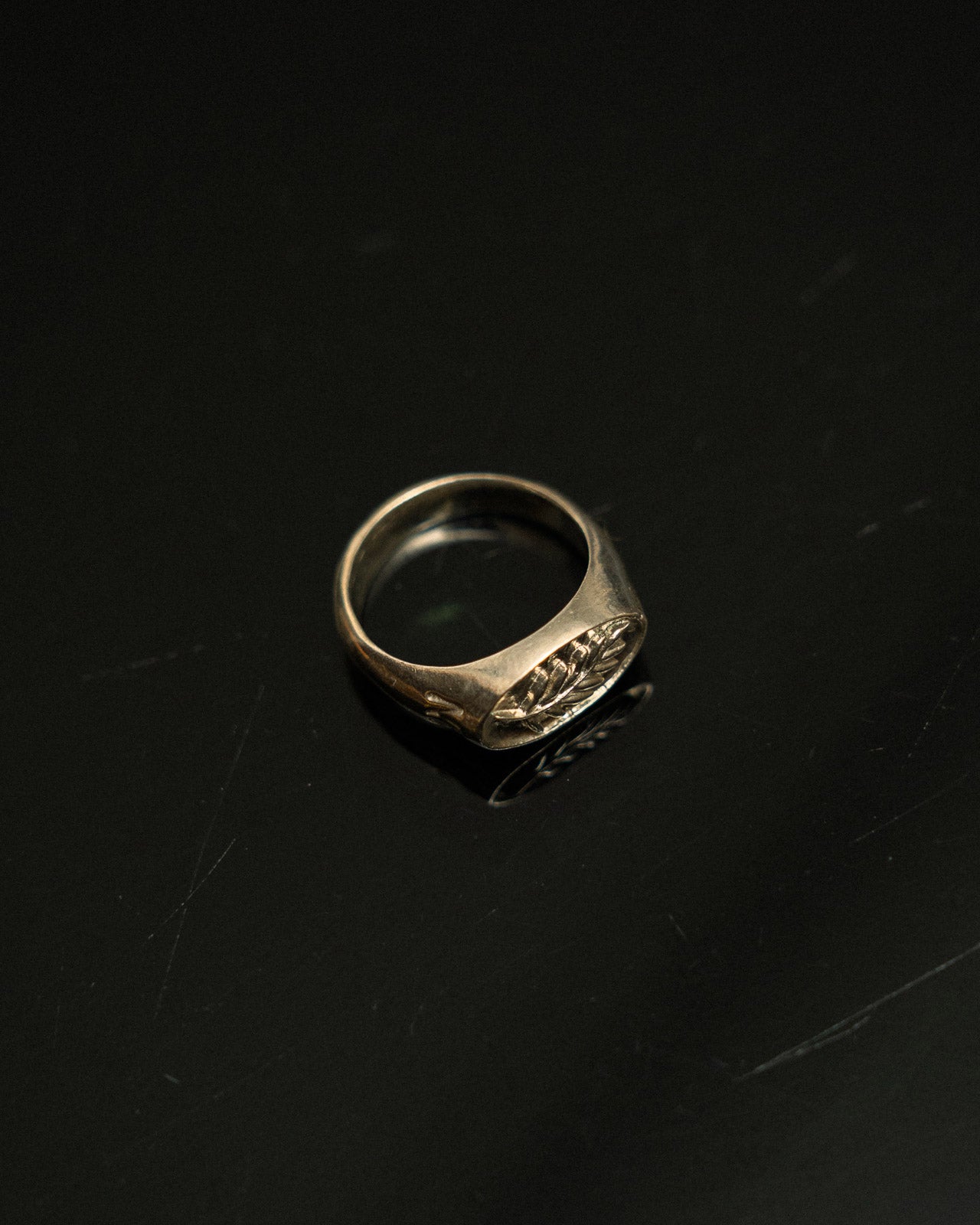 Silver ring with engraved design on a black background