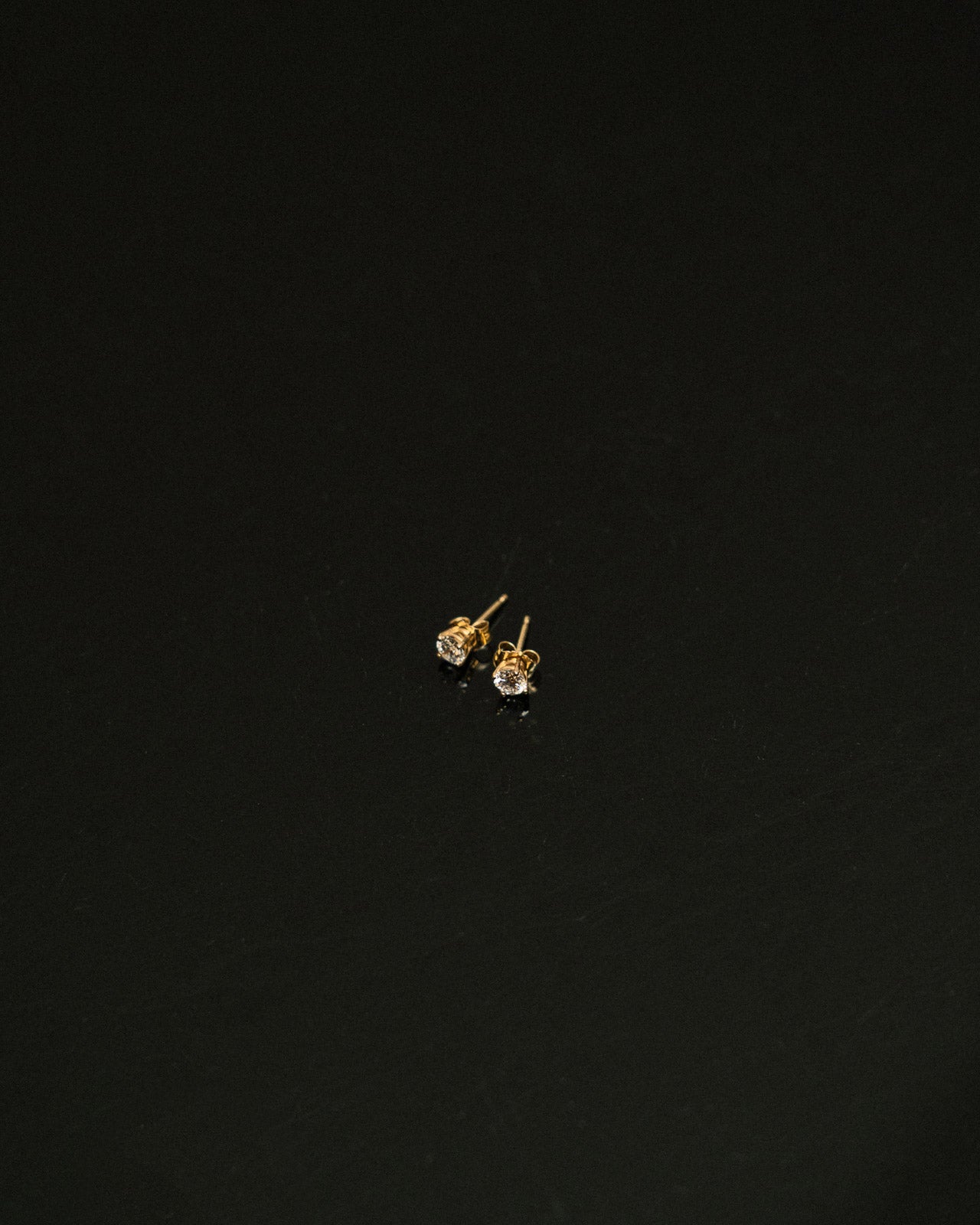 Gold earrings with clear gemstones on a black background