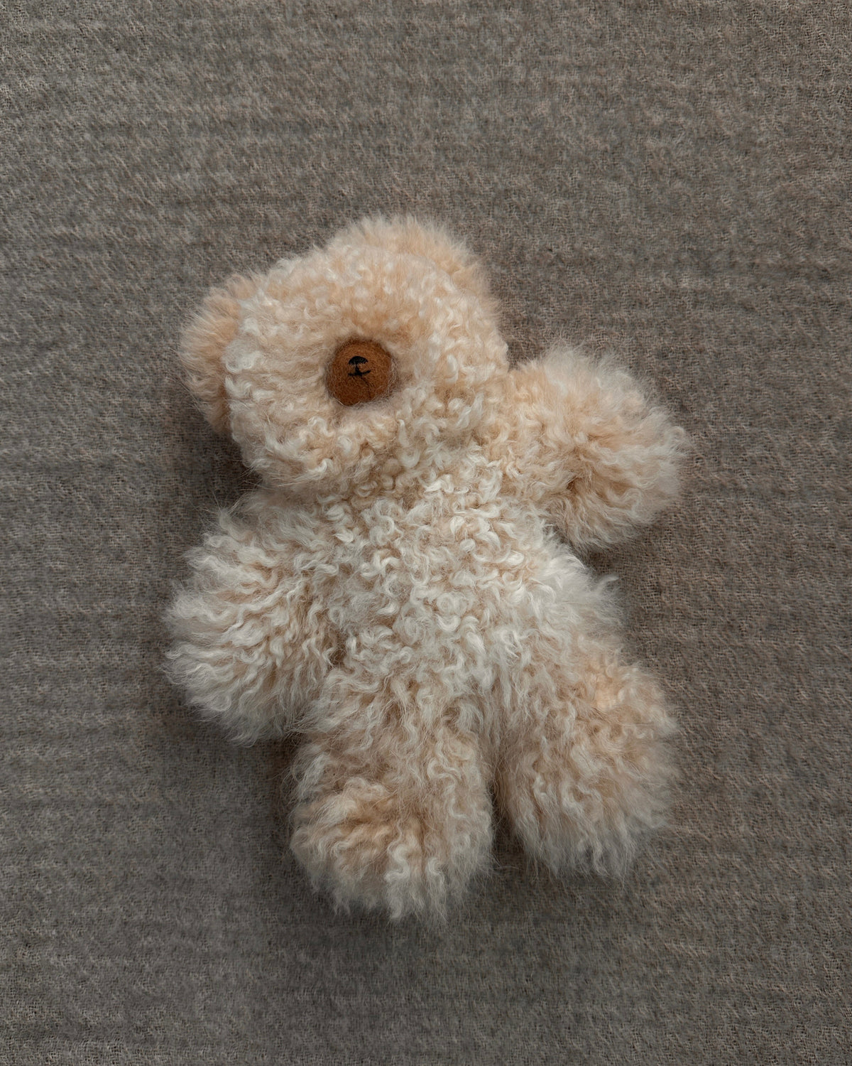 a small fawn teddy bear on a fabric background