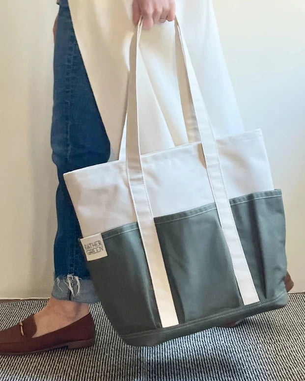 Person holding a green and white Rather Green Amiga tote bag against a neutral background