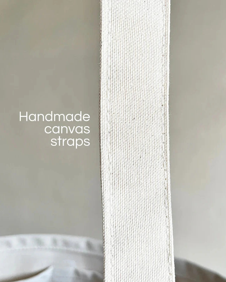 Close-up of a handmade canvas strap with text overlay on a neutral background