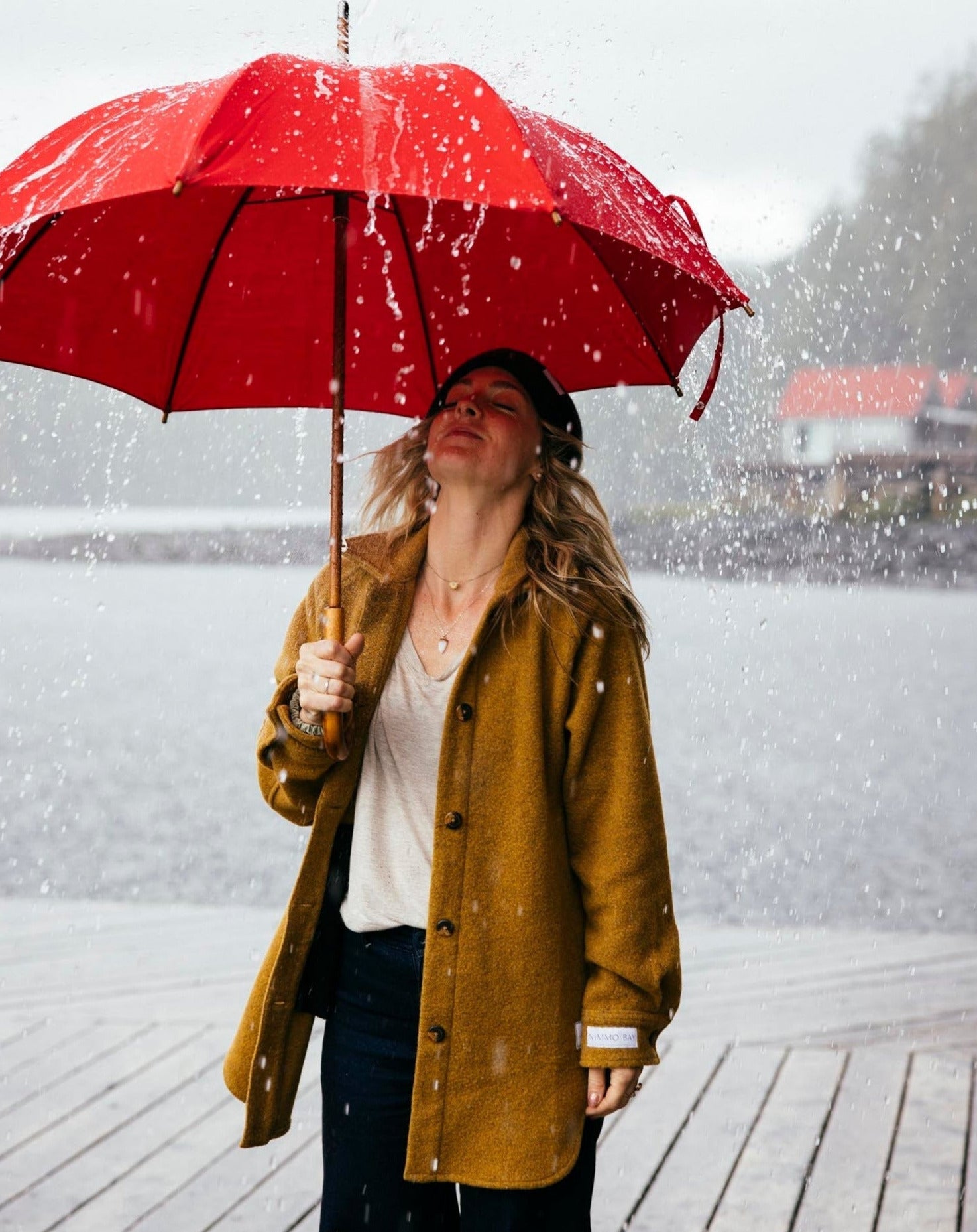 a woman standing in the rain with a red umbrella
