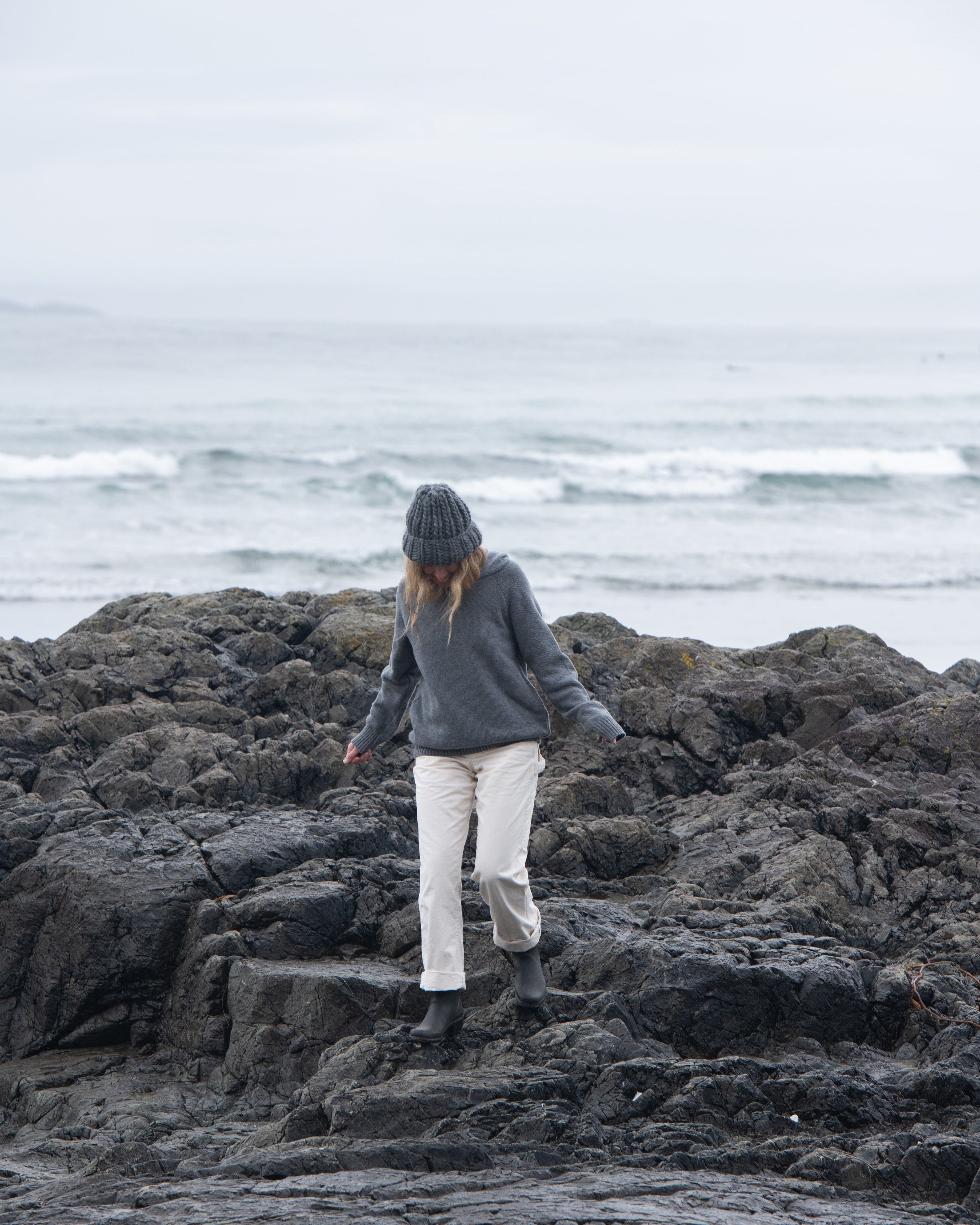 A woman on a Tofino beach wearing the Anian Cashmino Hoodie for Nimmo Bay