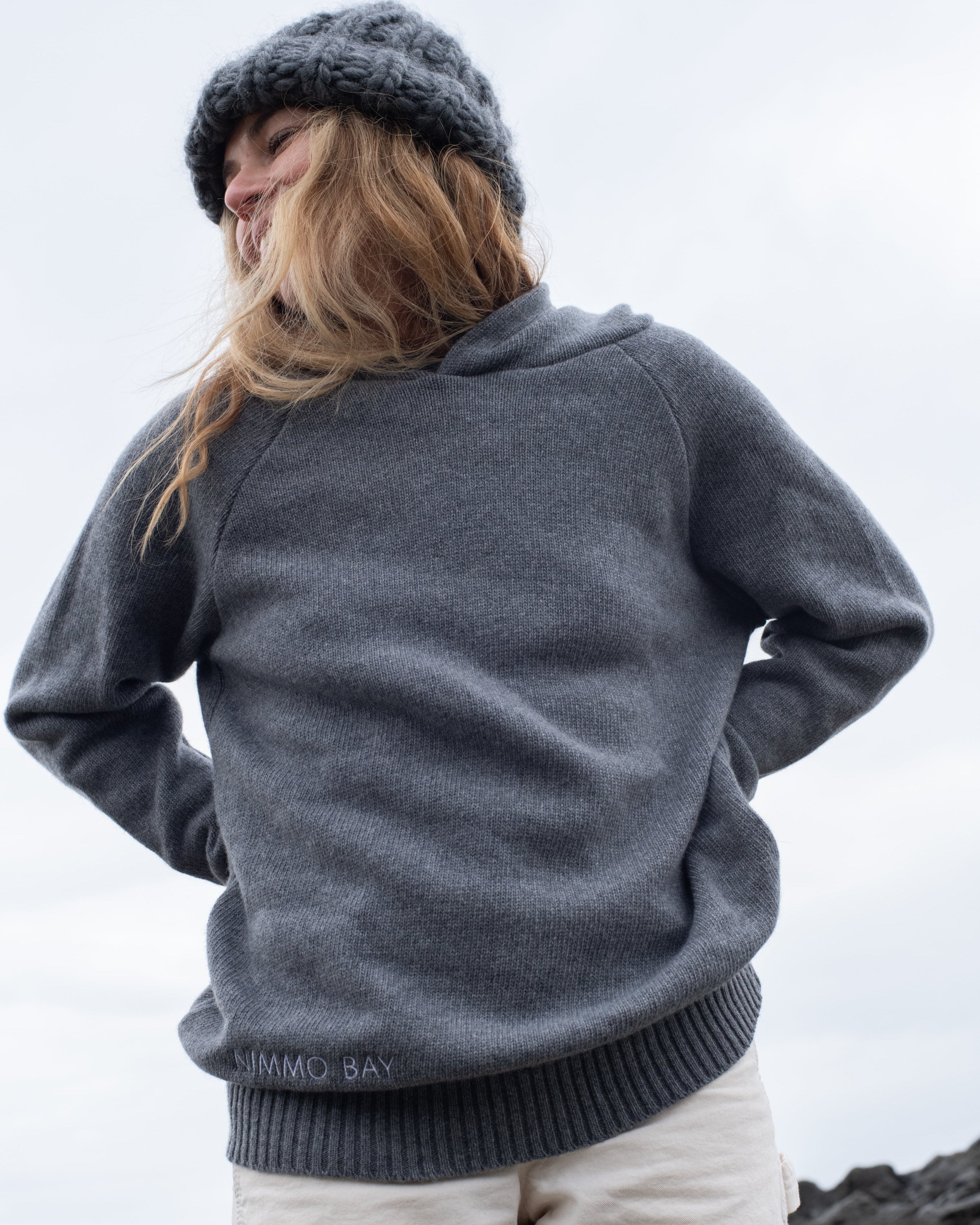 A woman on a Tofino beach wearing the Anian Cashmino Hoodie for Nimmo Bay