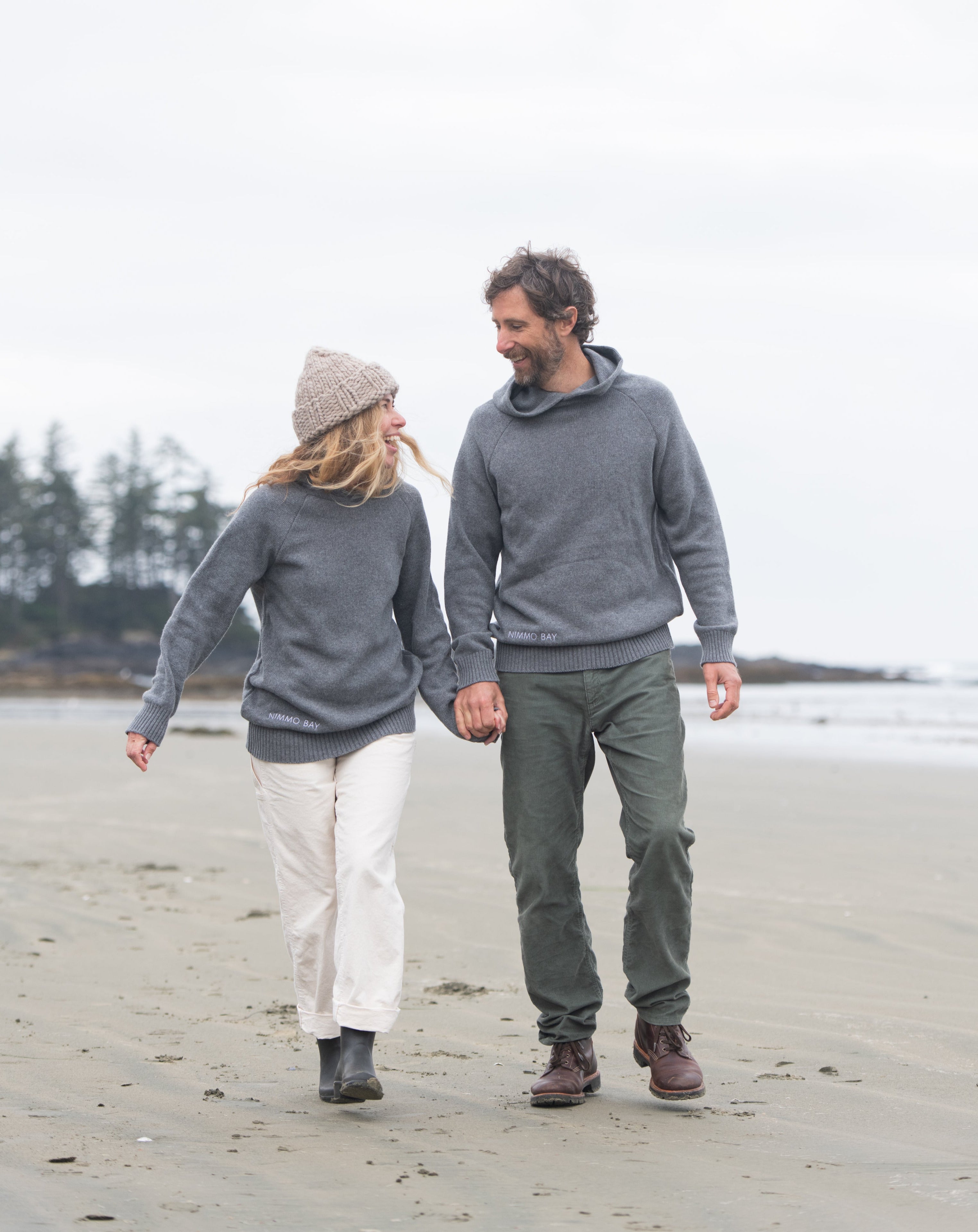 A couple on a Tofino beach wearing the Anian Cashmino Hoodie for Nimmo Bay