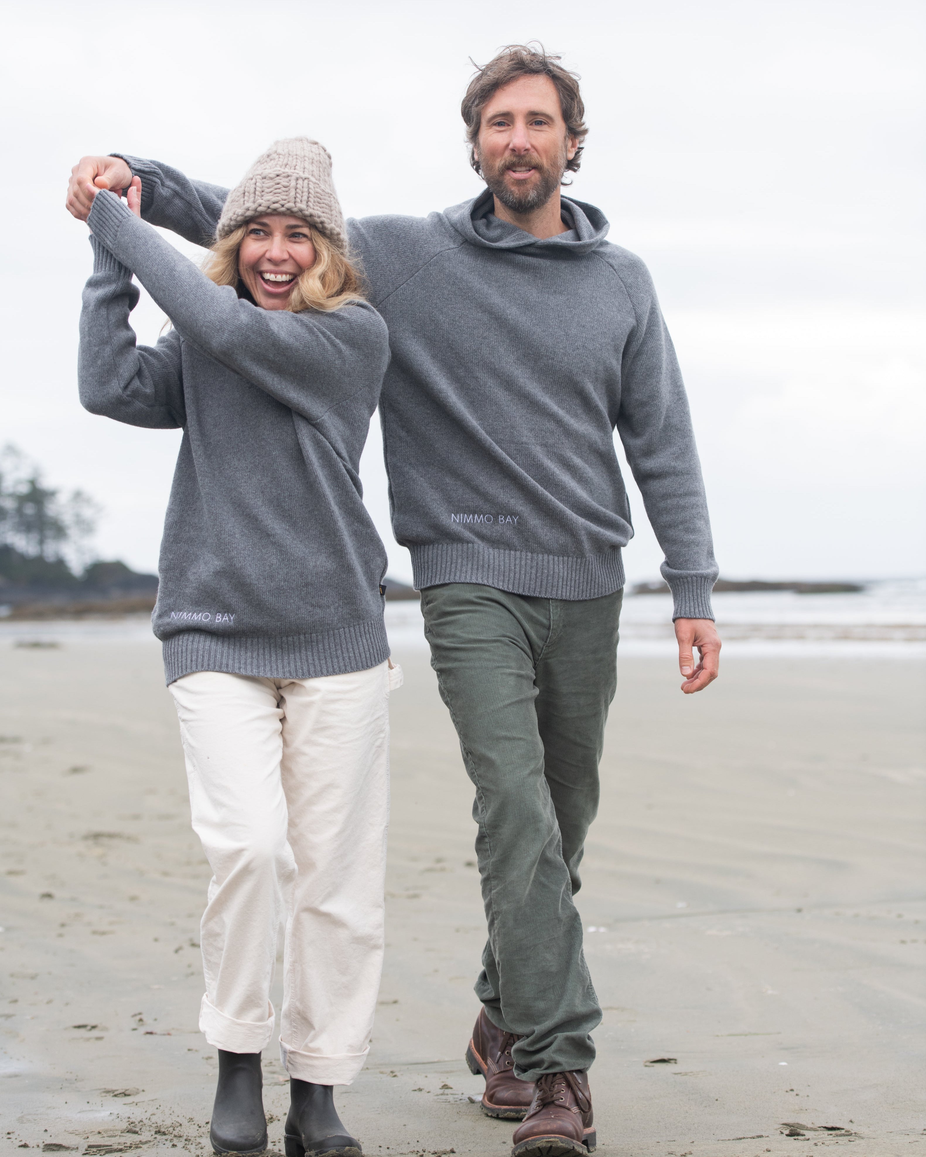 A couple on a Tofino beach wearing the Anian Cashmino Hoodie for Nimmo Bay