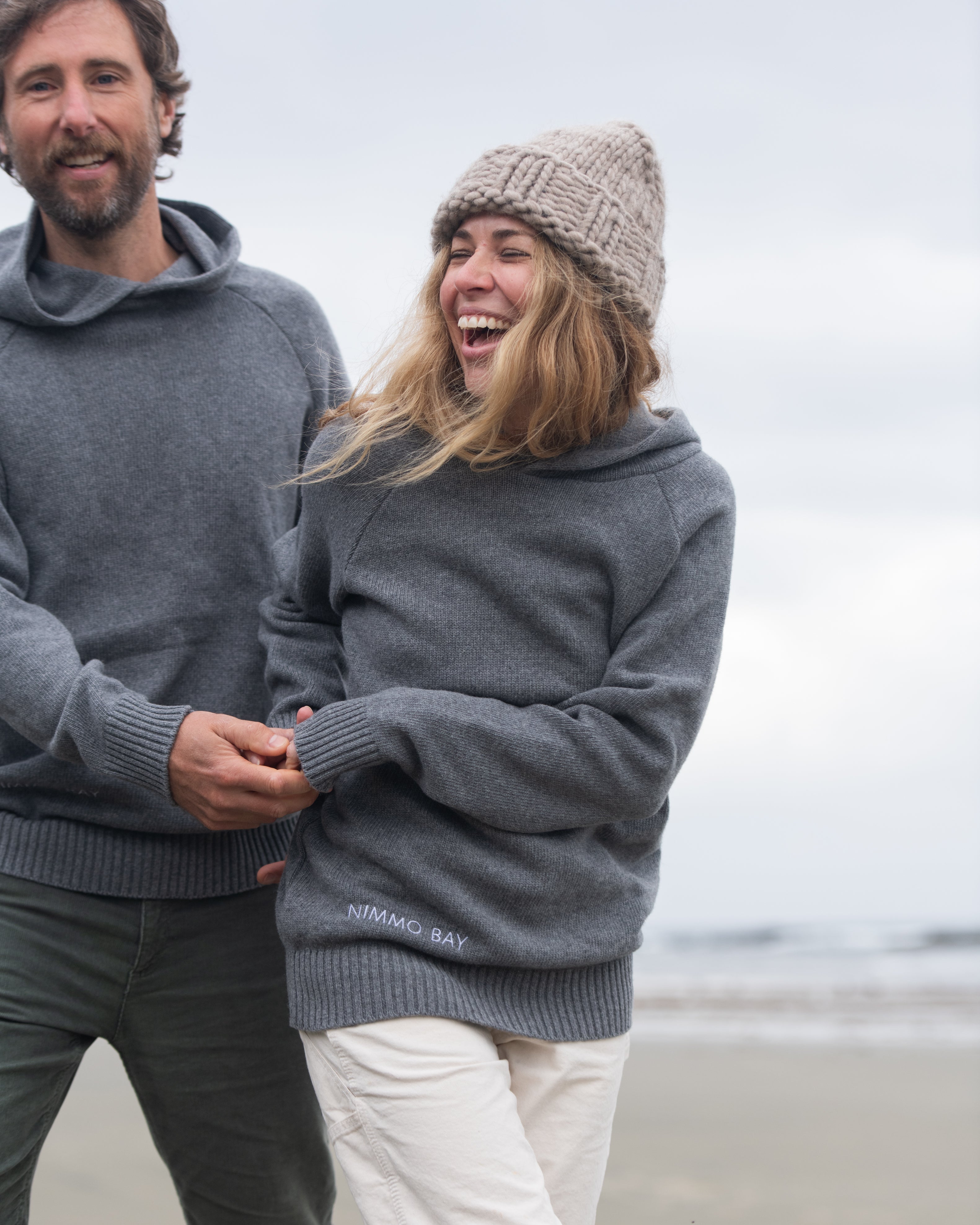 A couple on a Tofino beach wearing the Anian Cashmino Hoodie for Nimmo Bay