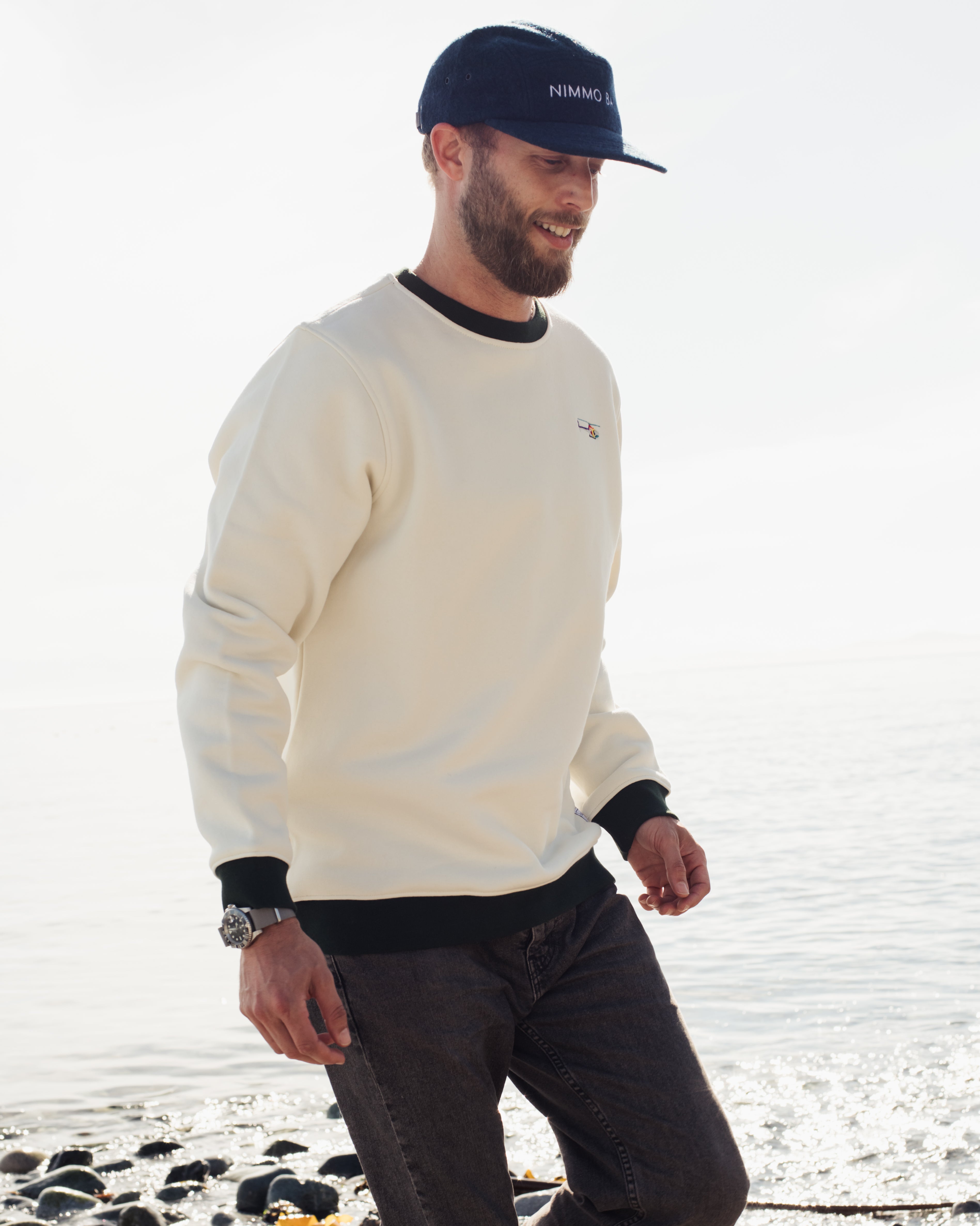 a man wearing the legacy crewneck sweater from anian in front of the ocean